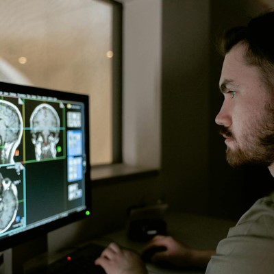 A man analyzing a brain scan on a computer screen, focusing on the intricate details of the image.