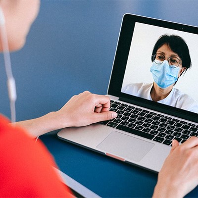 a woman wearing a face mask on a laptop