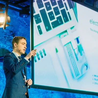 a man standing in front of a projector screen giving a presentation