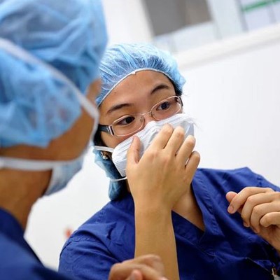a woman in scrubs and a surgical mask