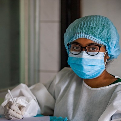 a woman in a surgical mask writing on a piece of paper